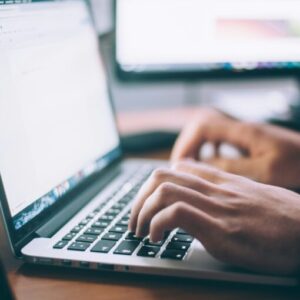 Close-up of hands typing on a laptop keyboard.