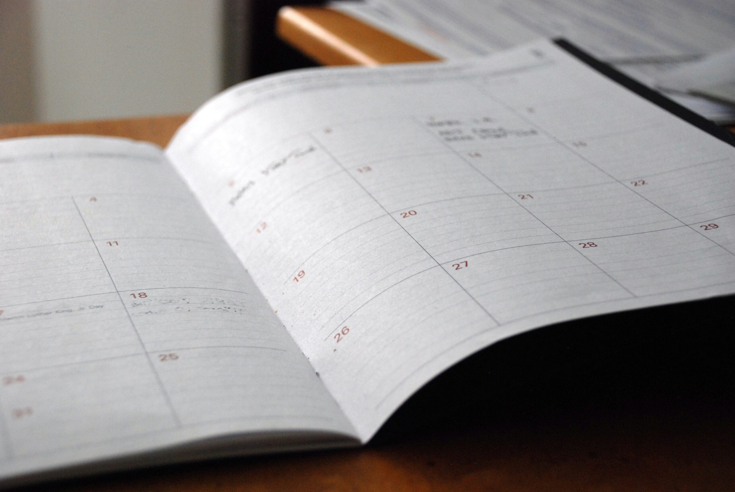 Open planner on a desk showing dates with handwritten notes.